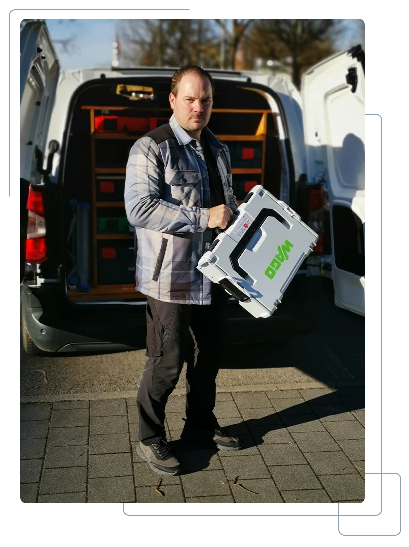 Porträt eines lächelnden Elektrikers im Arbeitsanzug am Kofferraum seines Transporters