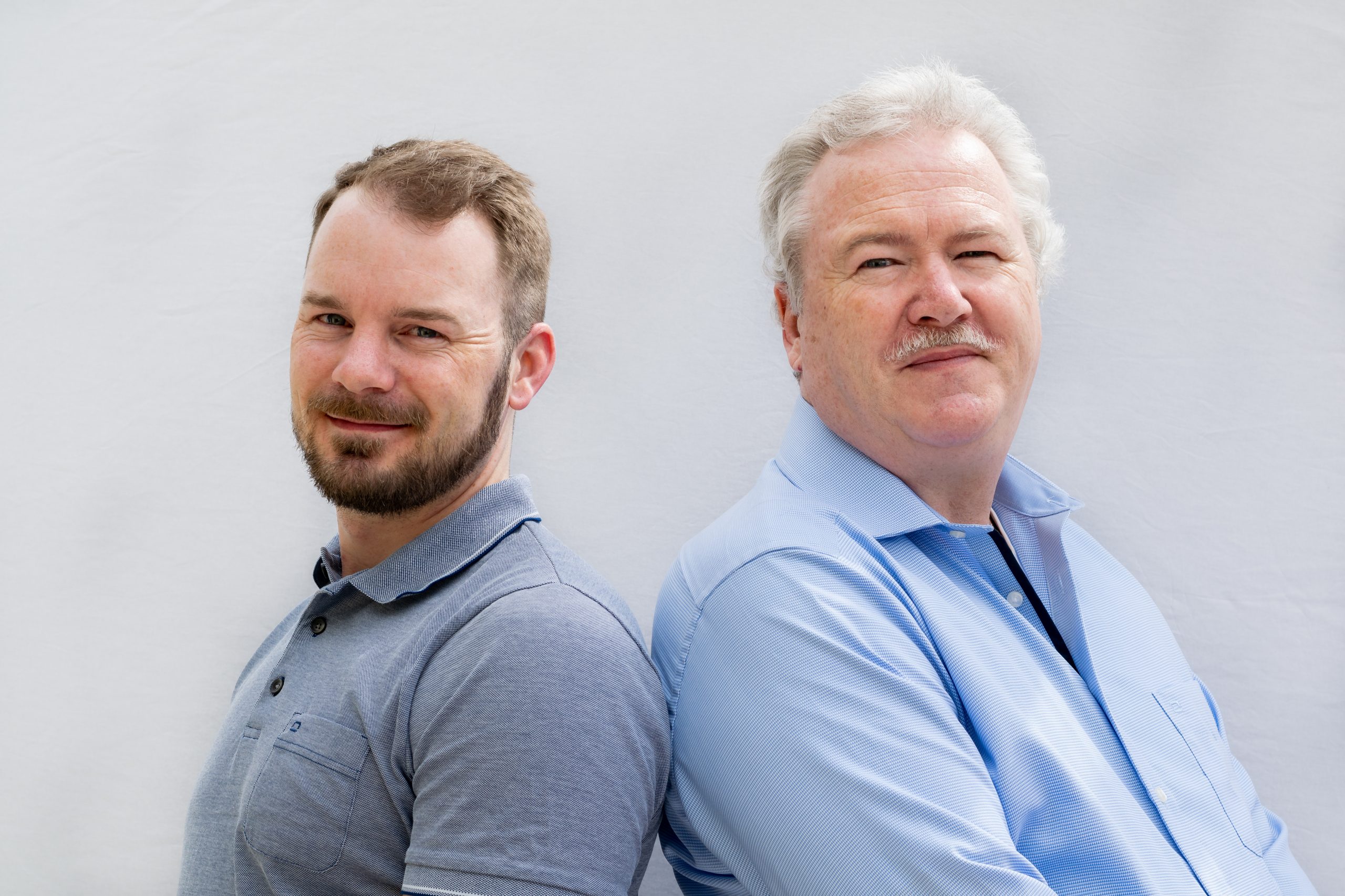 Portrait der Gründer und des Inhabers von PERFEMO Elektrotechnik, lächelnd vor neutralem Hintergrund